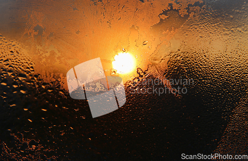 Image of Ice patterns, water drops and sunlight on a winter window glasss