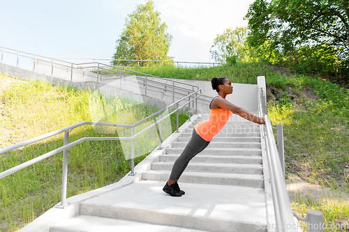 Image of young african woman doing push-ups outdoors