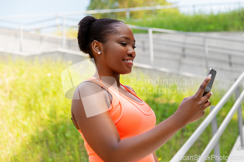 Image of sporty african woman using smartphone in city