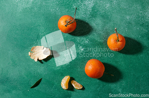 Image of still life with mandarins on green background