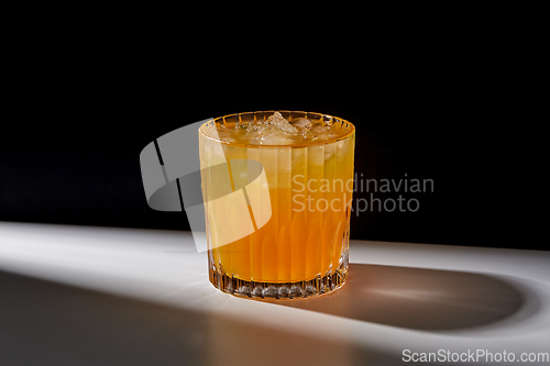 Image of glass of orange juice with ice on table