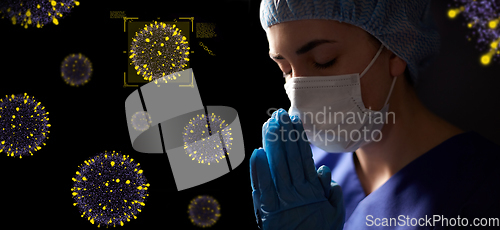 Image of female doctor or nurse in face mask praying