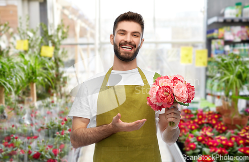 Image of smiling male gardener with peonies at flower shop