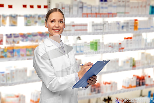 Image of smiling female doctor with clipboard at pharmacy