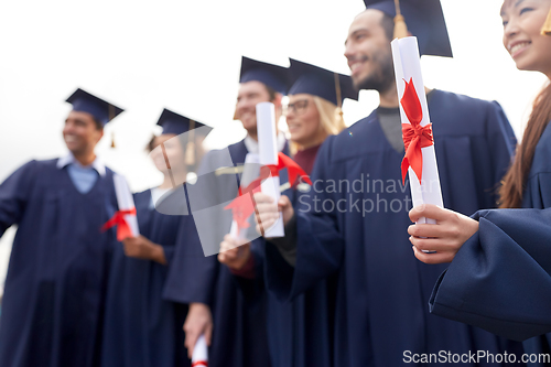 Image of graduate students in mortar boards with diplomas