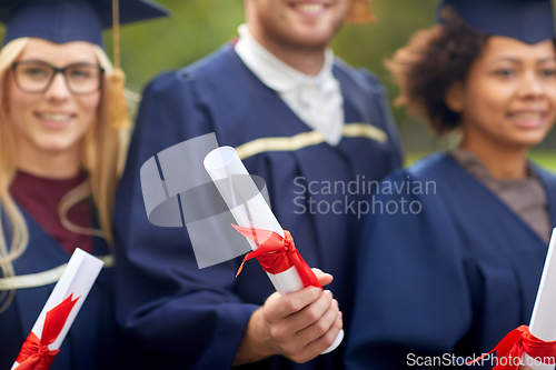 Image of graduate students in mortar boards with diplomas