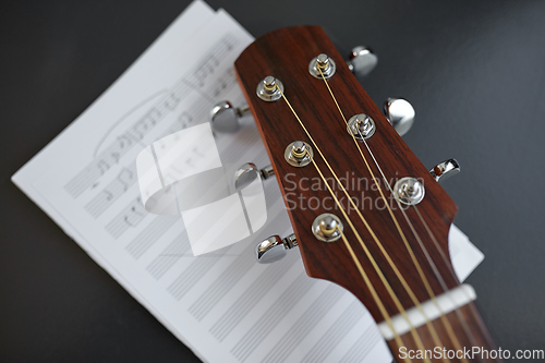 Image of close up of acoustic guitar head with music book