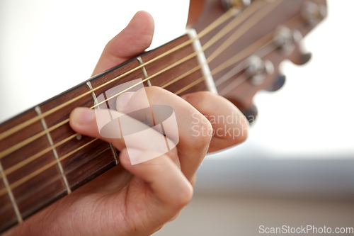 Image of close up of hand with guitar neck playing music