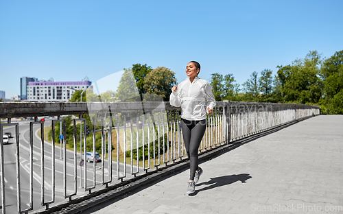 Image of african american woman running along bridge