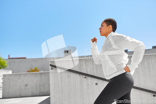 Image of african american woman running upstairs outdoors