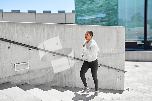 Image of african american woman running upstairs outdoors