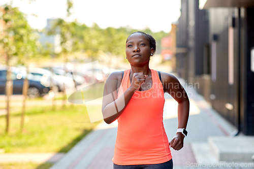 Image of african woman with smart watch running in city