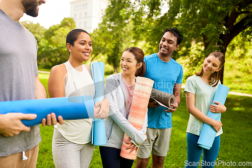 Image of group of happy people with yoga mats at park