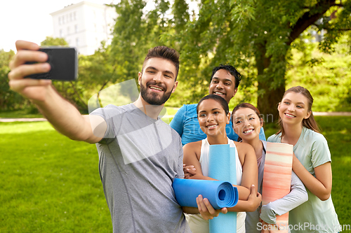 Image of people with yoga mats taking selfie at park