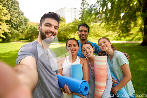 Image of people with yoga mats taking selfie at park