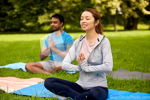 Image of group of people doing yoga at summer park