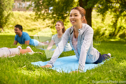 Image of group of people doing yoga at summer park