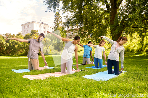 Image of group of people doing yoga at summer park