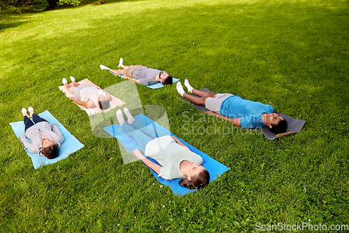 Image of group of people doing yoga at summer park