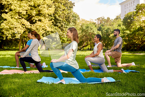 Image of group of people doing yoga at summer park