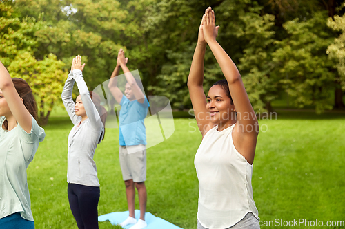 Image of group of people doing yoga at summer park