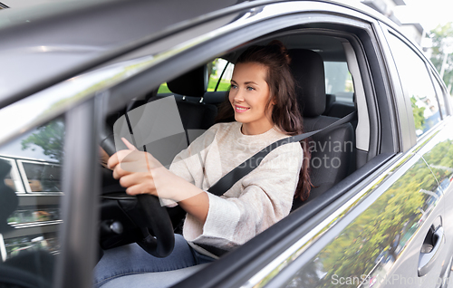 Image of smiling woman or female driver driving car in city