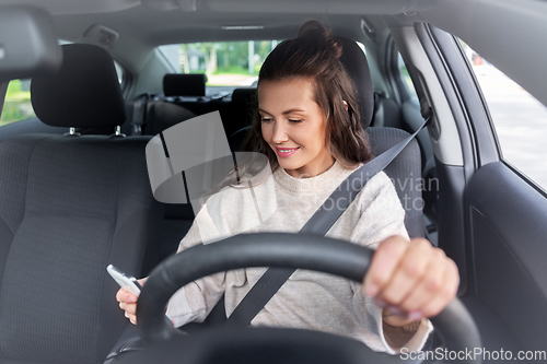 Image of smiling woman or female driver driving car in city