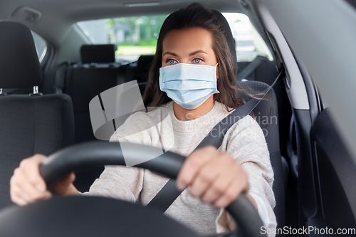 Image of woman or female driver in mask driving car in city