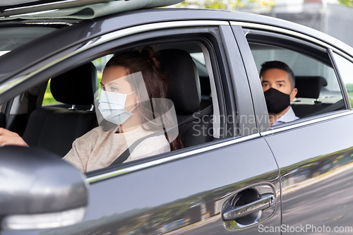 Image of female driver in mask driving car with passenger