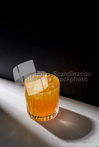 Image of glass of orange juice with ice on table