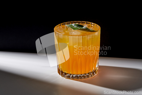 Image of glass of orange juice with ice on table