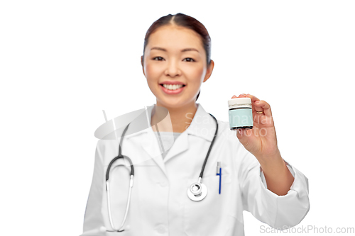 Image of smiling female doctor holding jar of medicine