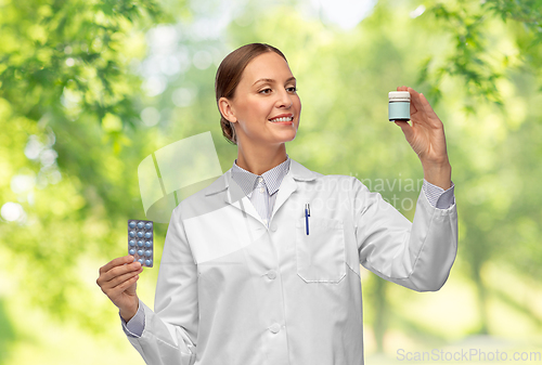 Image of smiling female doctor holding medicine pills