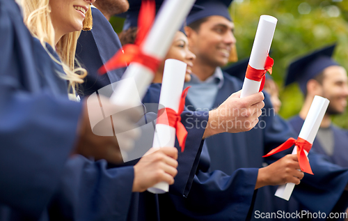 Image of graduate students in mortar boards with diplomas