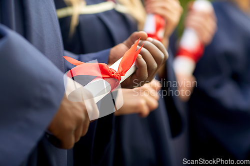Image of graduate students in mortar boards with diplomas