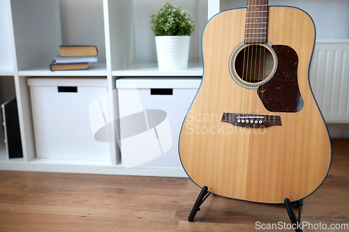 Image of close up of acoustic guitar on stand at home