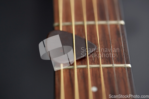 Image of close up of guitar neck with pick between strings