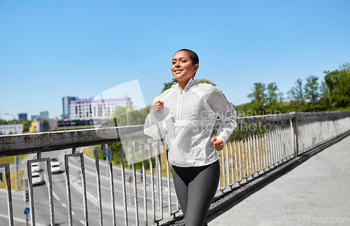 Image of african american woman running along bridge