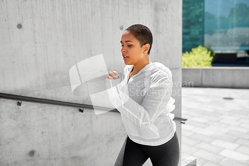 Image of african american woman running upstairs outdoors