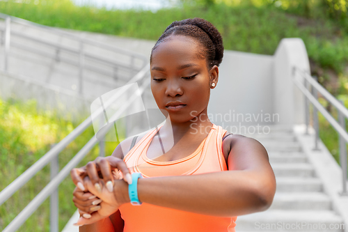 Image of african woman with fitness tracker outdoors