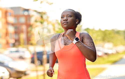 Image of african woman with smart watch running in city