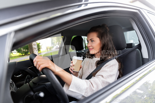 Image of woman or female driver with coffee driving car