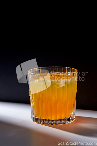 Image of glass of orange juice with ice on table