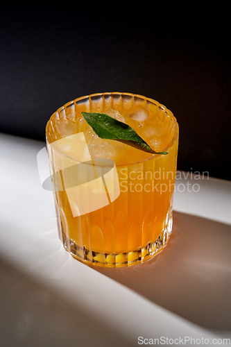 Image of glass of orange juice with ice on table