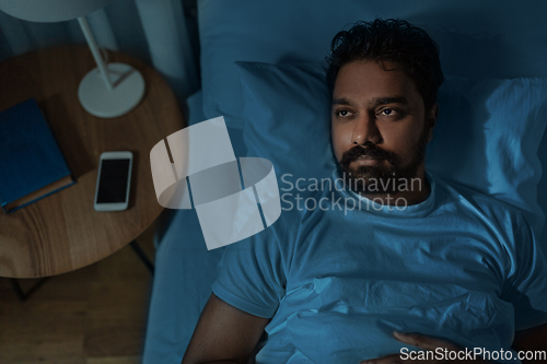 Image of speelpess indian man lying in bed at night