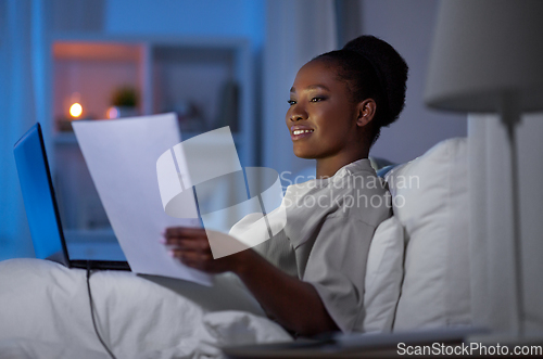 Image of woman with laptop working in bed at night