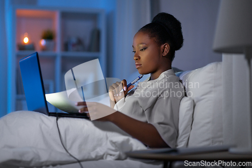 Image of woman with laptop working in bed at night