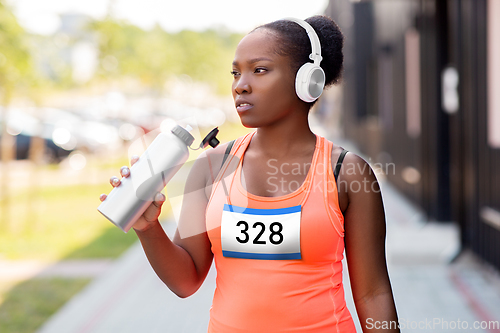 Image of african female marathon runner drinking water