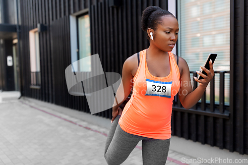 Image of female marathon runner with smartphone stretching