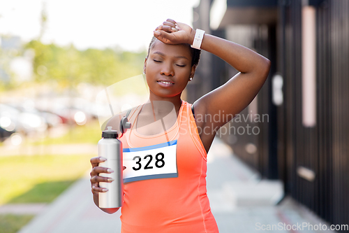 Image of tired female marathon runner with bottle of water